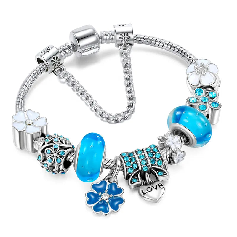 Elegant blue charm bracelet with sterling silver floral beads, glass charms, and heart pendant inscribed with 'Love' – perfect women’s jewelry accessory.
